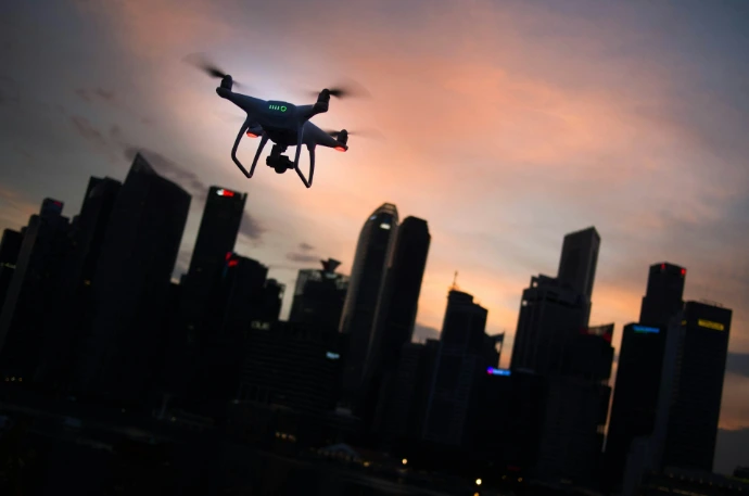 silhouette of quadcopter drone hovering near the city